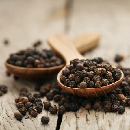 Twee hoopjes zwarte peper op houten lepels